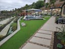 Photo of a yard with artificial turf, a walkway, and a pool.